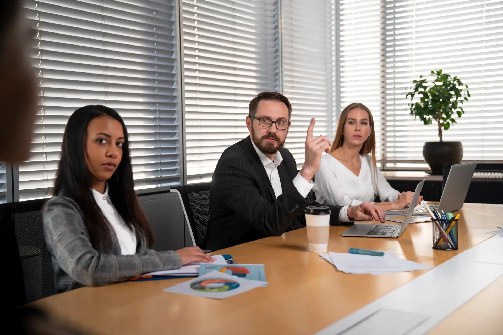 Equipe de profissionais discutindo estratégias de consultoria jurídica para fintechs em uma reunião de negócios, com laptops e documentos na mesa.
